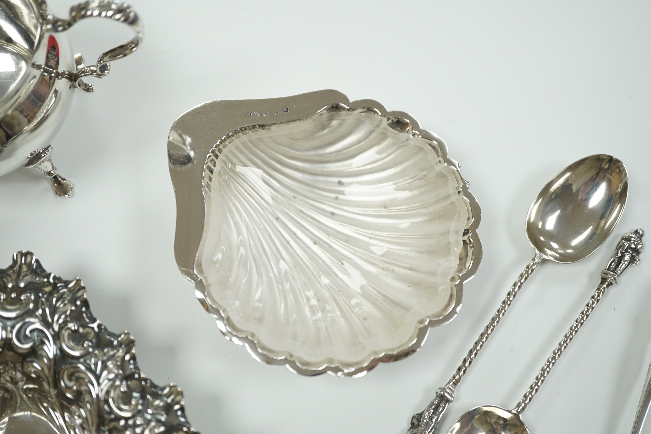 A small group of collectable silver including a repousse bonbon dish, 13.5cm, cigarette case, silver cream jug and sugar bowl, butter shell, vesta case, match sleeve, two apostle teaspoons and a George III curved silver